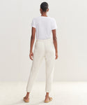 A woman stands with her back to the camera wearing a plain white T-shirt, Saturday Sweatpant joggers in ultra-soft French terry, and tan moccasin slippers against a light, neutral background.