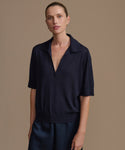 Woman wearing a dark navy courtney top against a brown background