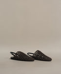 The Crochet Jules Mule slip-on sandals feature a black crochet design with a closed toe, open heel, and are displayed on a neutral beige background.