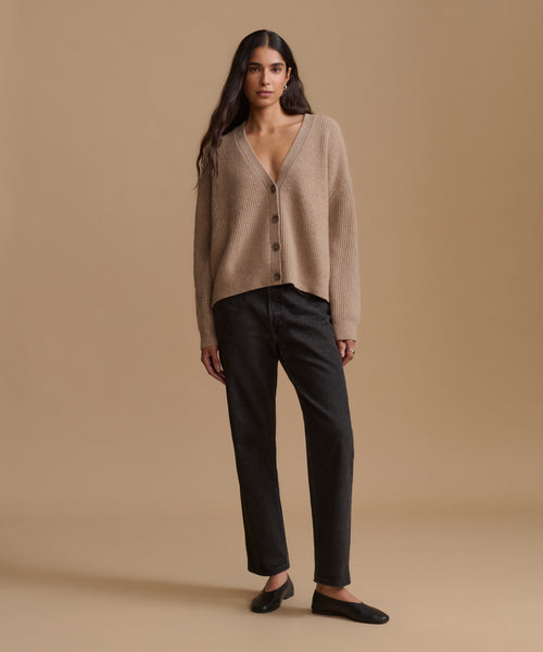A woman wearing a taupe ribbed knit button-front cardigan sweater against a solid beige background.
