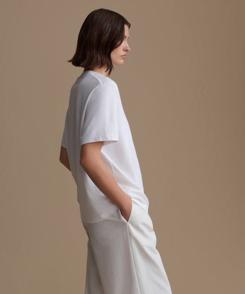 Person wearing a white outfit against a beige background