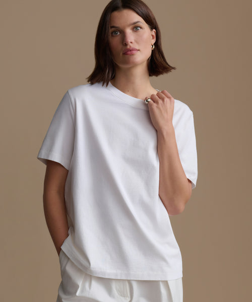 Woman wearing a white t-shirt against a beige background