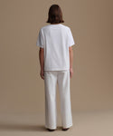 Person wearing a white t-shirt and pants on a beige background