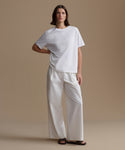 Person wearing a white t-shirt and pants on a beige background