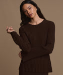 A woman with long dark hair wears the Dara Top in dark brown, standing against a plain brown background. She gazes forward with a neutral expression and has one hand slightly raised.