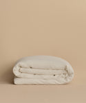 The Dusk Linen Duvet Cover is a lightweight, off-white linen cover featuring a subtle textured pattern, displayed against a plain beige background.