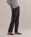 A person stands sideways with one hand on their hip, wearing a gray sweater and the Easy Straight Crop luxury jeans in a mid rise, straight cropped fit, paired with brown flat shoes against a neutral background. Their face is not visible.