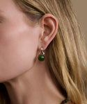 Close-up of a woman wearing a green bead earring with a beige background
