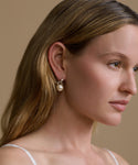 Close-up of a woman wearing a pearl earring against a beige background