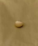 The Felix Dome Ring, featuring a smooth gold dome design, is displayed on a softly textured light tan fabric background.