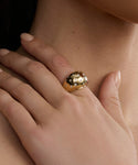 A hand with neatly manicured nails rests on a neck, showcasing the Diamond Felix Dome Ring on the index finger.