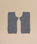 A pair of Fingerless Cashmere Gloves in grey is laid flat side by side on a beige background.