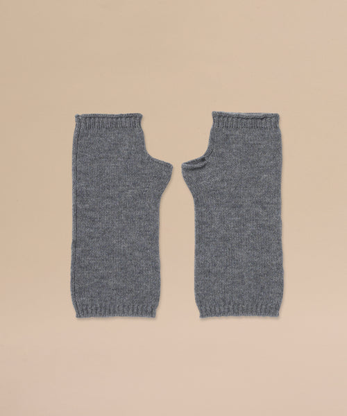 A pair of Fingerless Cashmere Gloves in grey is laid flat side by side on a beige background.