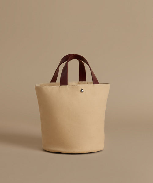 Beige tote bag with brown handles on a beige background