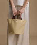 Person holding a beige tote bag against a beige background