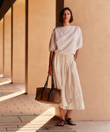 Woman holding a brown handbag against a beige wall
