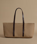 Beige tote bag with dark brown straps on a beige background