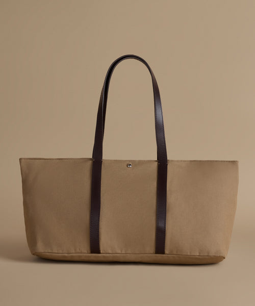 Beige tote bag with dark brown straps on a beige background