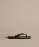 A single Gia Sandal in black with a simple strap design is shown on a plain beige background—ideal for effortless summer style.
