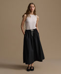 Woman wearing a white sleeveless top and black skirt on a beige background