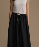 Woman wearing a black skirt with a white top on a brown background