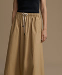 Woman wearing a long beige skirt with a plain background