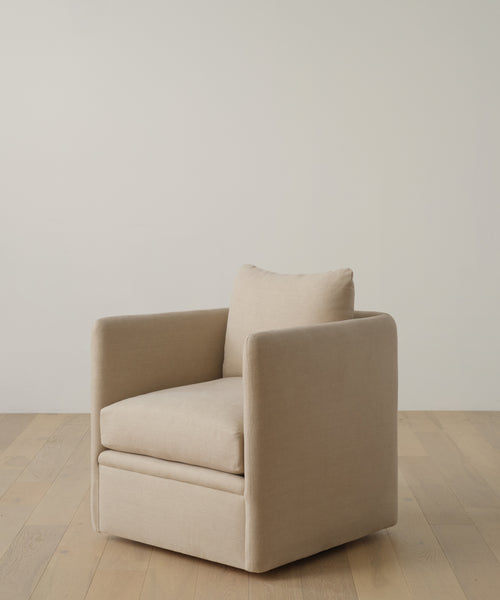 The Dume Chair is a modern, sustainable accent piece in beige hemp with clean lines, a boxy silhouette, and a single cushion. It sits on a light wood floor against an off-white wall.