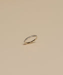 The Iris Eternity Band is a slim 14k solid gold ring featuring small, evenly spaced conflict-free diamonds around the band, shown against a simple beige background.
