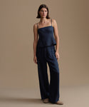 Woman wearing a navy kinney cami and pants against a beige background