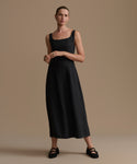 Woman wearing a black sleeveless dress against a beige background