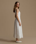 Woman wearing a white dress with cut-out back on a beige background