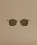 Sunglasses with a green frame and brown lenses on a beige background