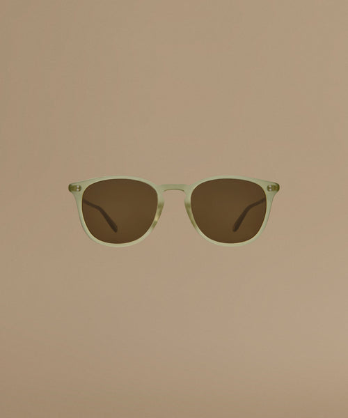 Sunglasses with a green frame and brown lenses on a beige background