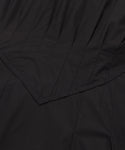 Close-up of black fabric with visible stitching and pointed, layered seam detail. The smooth, slightly shiny material hints at a refined summer staple—perfect for the Kit Dress.