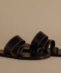 Pair of black leather sandals on a beige background