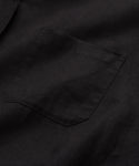 A close-up of the Linen Logan Shirt in black highlights its classic style, with a small chest pocket and simple stitching that emphasize its relaxed design.