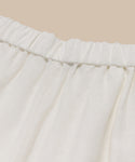 Close-up of the Linen Logan Pants ivory waistband, highlighting gathered linen fabric against a beige background—ideal for effortless everyday style.