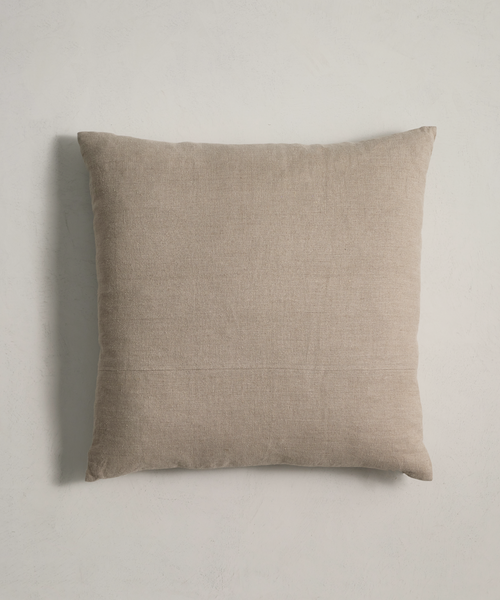 A square, light beige Linen Pillow with a natural linen texture is set against a plain light-colored background.