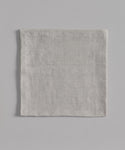 A neatly folded light gray Linen Tablecloth featuring thin horizontal stripes and a subtle black stripe, displayed on a flat light gray background.