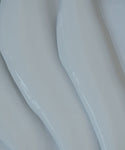Close-up of smooth, white, wavy, glossy surfaces with soft curves—resembling abstract shapes or flowing material—much like the silky texture of Luminous Body Lotion Travel.