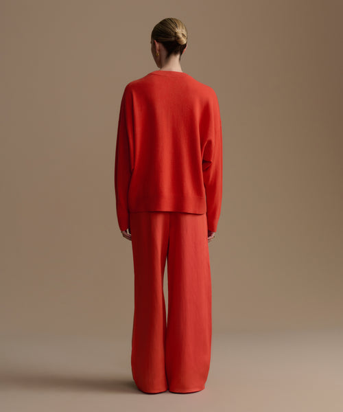 Woman wearing a red outfit standing against a beige background
