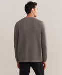 A man stands with his back to the camera, wearing a gray Mens Cashmere Cardigan and black pants against a plain light background.