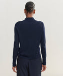 A person with their hair in a bun is shown from the back against a plain, light background, wearing a dark navy Grayson Pullover and matching pants.