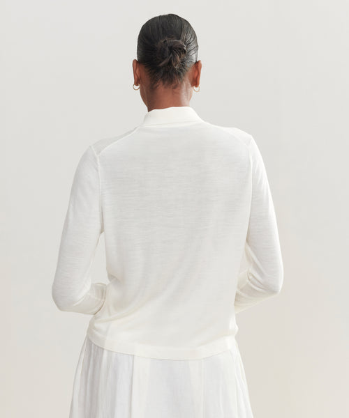 A person with dark hair in a neat bun, wearing the Grayson Pullover and a matching skirt, is shown from behind against a plain light background.