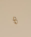 Two Merit Baguette Hoops, crafted in 14k recycled gold with rectangular gems, sit side by side on a plain beige background, highlighting their elegant design.