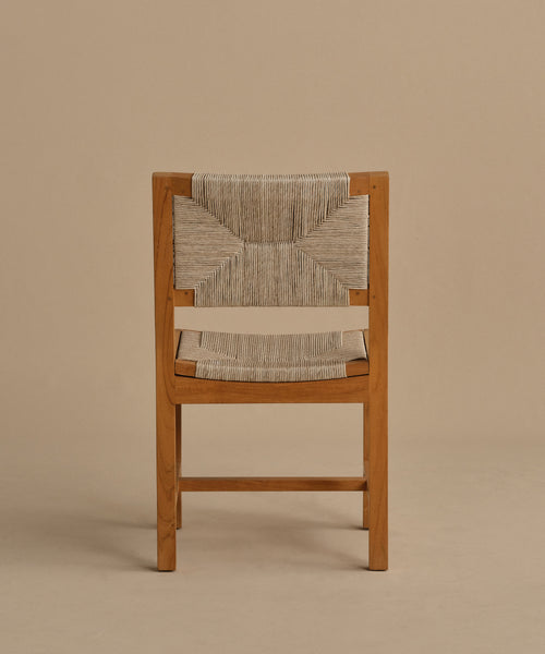 The Outdoor Montecito Dining Chair Frame, crafted from teak with a woven seat and backrest in a light geometric cord pattern, is displayed against a plain beige background and viewed directly from the back.