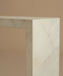 A a close up of a minimalist console table made of light beige parchment with subtle white veining, set against a solid warm beige background.