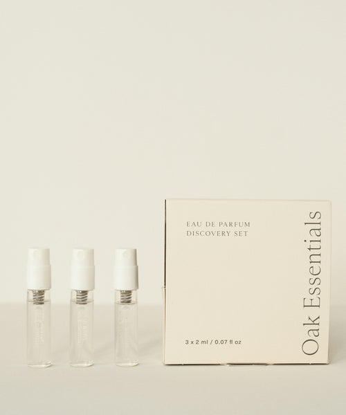 Three small clear perfume vials stand beside a cream-colored box labeled Eau De Parfum Discovery Set, ideal for exploring signature scents, all displayed against a light background.