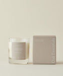 A Violet Santal Candle, with a minimalist light design, is set against a neutral backdrop that reflects coastal nostalgia and the calming spirit of California woods.