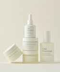 The Routine by Oak Essentials, featuring jars, a dropper bottle, and a spray bottle in minimalist packaging, is arranged on a neutral background to showcase the 5-step regimen for glowing skin.